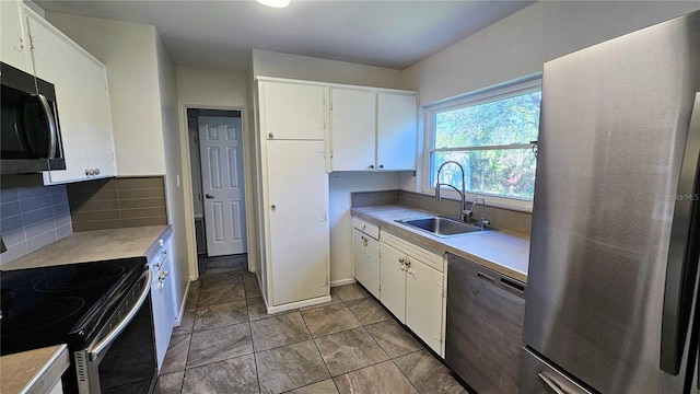 kitchen with light countertops, appliances with stainless steel finishes, a sink, and tasteful backsplash