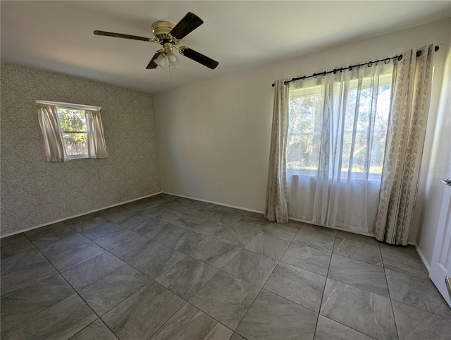 spare room with ceiling fan, baseboards, and wallpapered walls