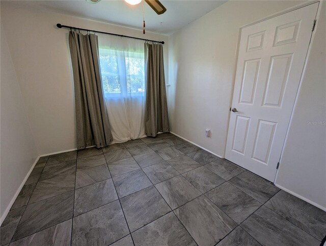 unfurnished room with a ceiling fan and baseboards