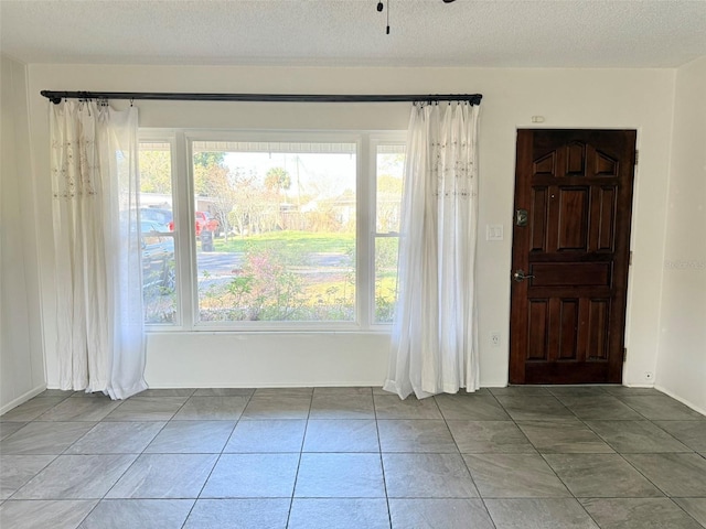 tiled empty room with a healthy amount of sunlight and a textured ceiling