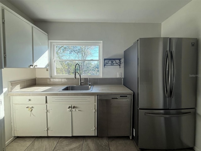 kitchen featuring stainless steel appliances, light countertops, a sink, and white cabinetry