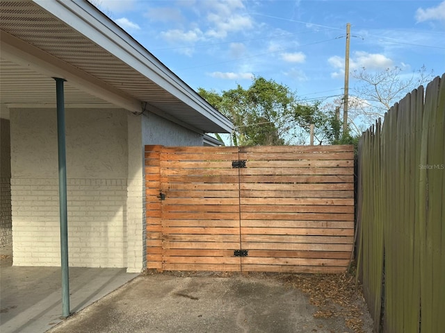 view of gate with fence and a patio