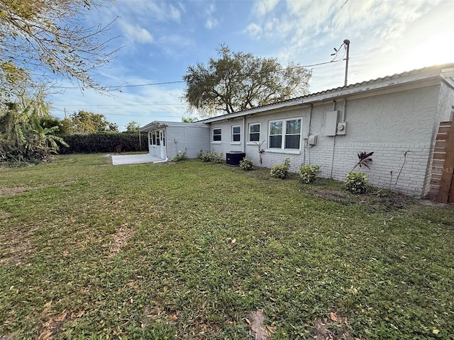 back of house with a yard, brick siding, and central AC unit