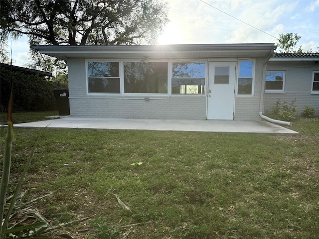 back of house with a yard, brick siding, and a patio area