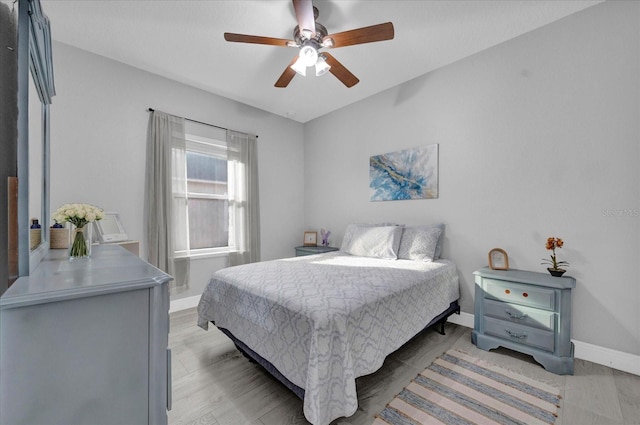 bedroom featuring ceiling fan, light wood-style floors, and baseboards