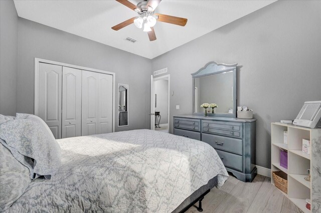 bedroom featuring ceiling fan, visible vents, baseboards, light wood-style floors, and a closet