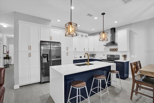 kitchen with stainless steel appliances, a sink, visible vents, white cabinets, and wall chimney exhaust hood