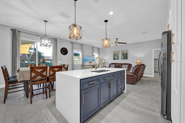 kitchen featuring a sink, visible vents, open floor plan, freestanding refrigerator, and light wood finished floors