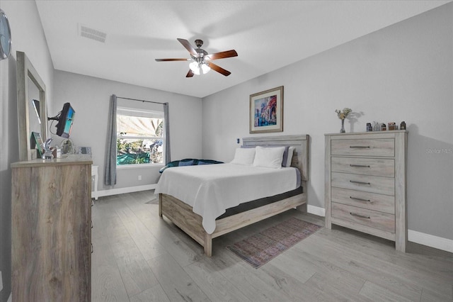 bedroom with wood finished floors, visible vents, and baseboards