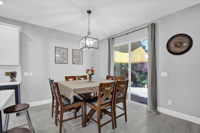 dining space featuring a notable chandelier, light wood finished floors, and baseboards