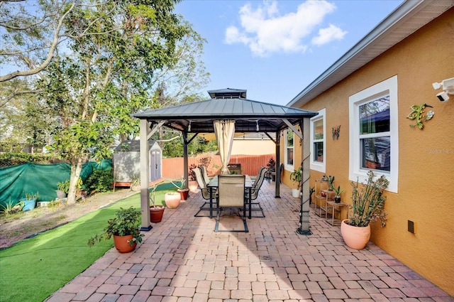 view of patio with a fenced backyard, an outbuilding, a storage unit, a gazebo, and outdoor dining space