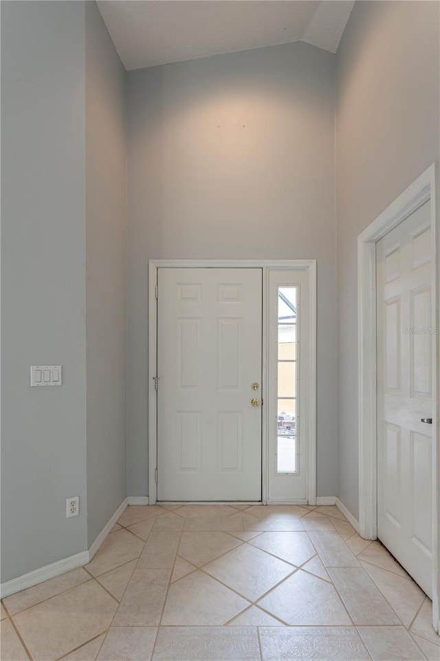 entryway featuring light tile patterned floors, high vaulted ceiling, and baseboards