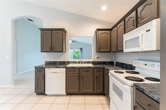 kitchen featuring light tile patterned flooring, vaulted ceiling, a sink, dark brown cabinetry, and white appliances