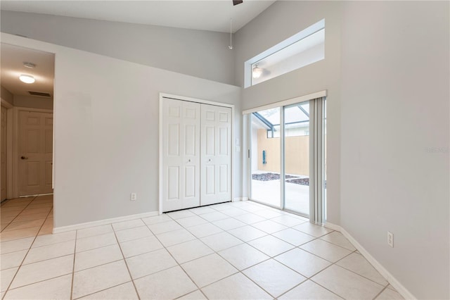 unfurnished bedroom featuring access to exterior, a closet, light tile patterned flooring, and baseboards