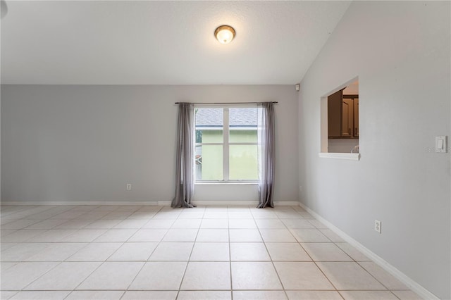 spare room featuring light tile patterned floors, baseboards, and a textured ceiling