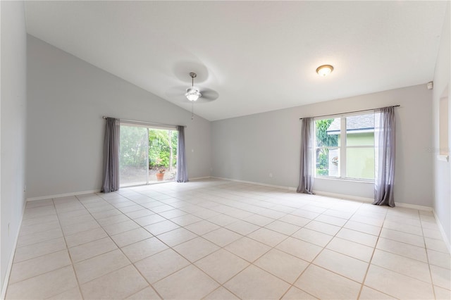 spare room with a wealth of natural light, vaulted ceiling, and light tile patterned floors