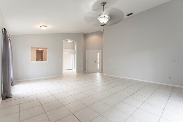 unfurnished room with a ceiling fan, arched walkways, baseboards, and light tile patterned floors