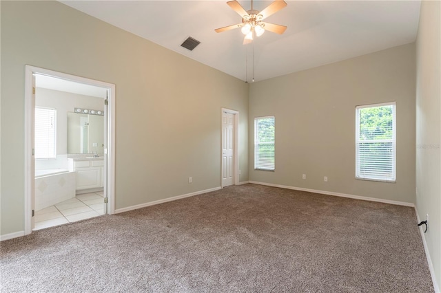 unfurnished bedroom featuring lofted ceiling, visible vents, carpet flooring, ensuite bath, and baseboards