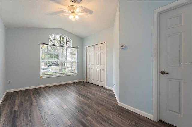 unfurnished bedroom featuring dark wood-style floors, baseboards, vaulted ceiling, and a closet