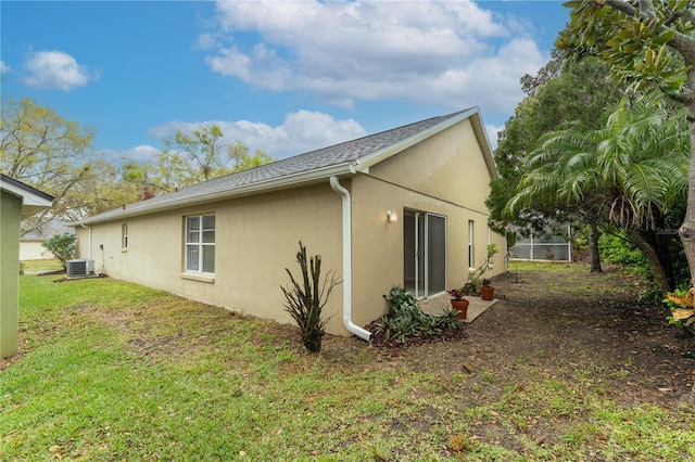 view of side of home featuring cooling unit, a lawn, and stucco siding