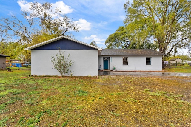 rear view of house featuring a yard and stucco siding