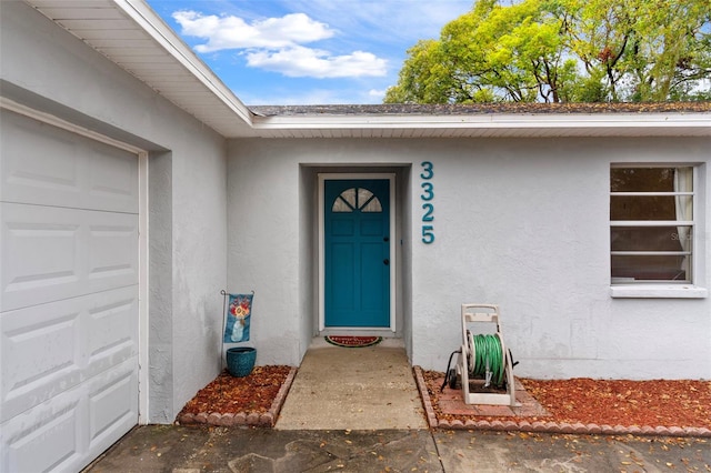 doorway to property featuring a garage and stucco siding