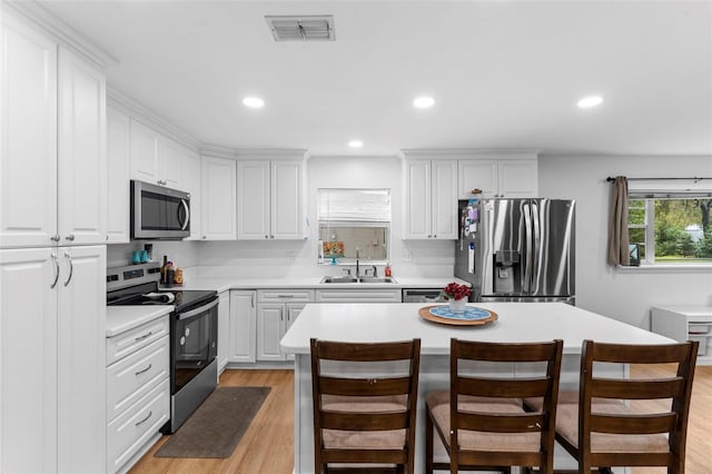 kitchen with light wood finished floors, visible vents, stainless steel appliances, light countertops, and a sink