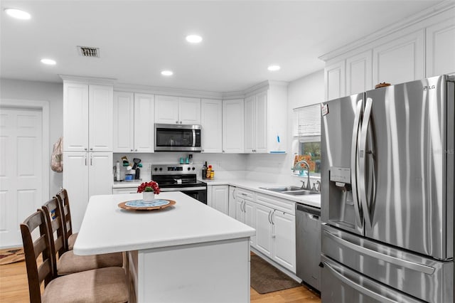 kitchen with stainless steel appliances, a sink, visible vents, white cabinets, and a kitchen breakfast bar