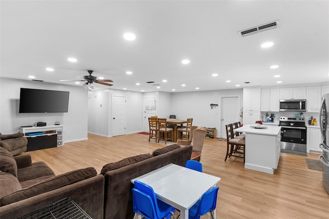 living room featuring light wood-type flooring, visible vents, and recessed lighting