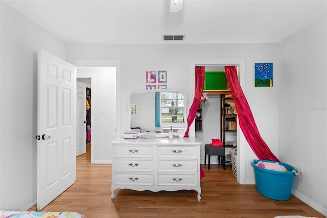 bedroom with light wood-style floors, visible vents, and baseboards