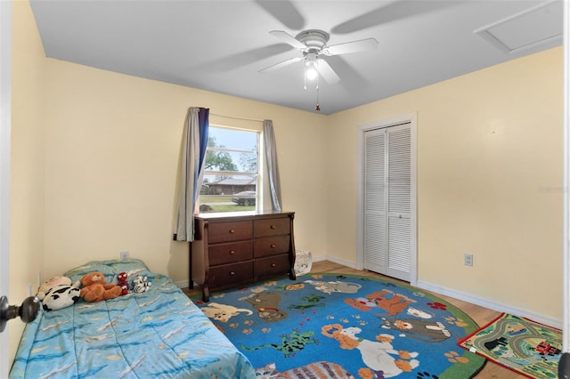 bedroom featuring attic access, baseboards, ceiling fan, wood finished floors, and a closet