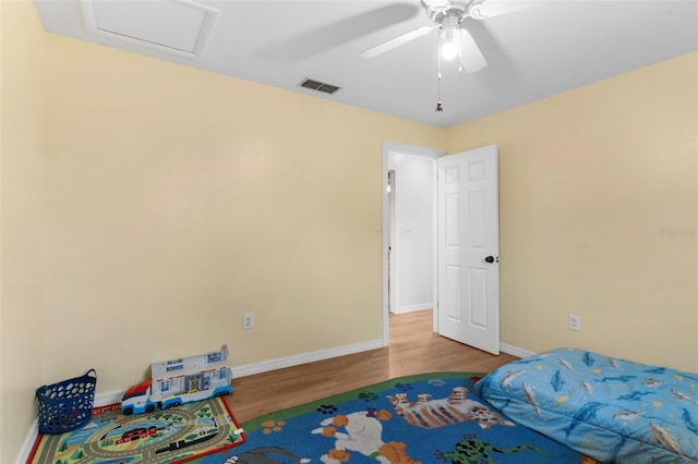 bedroom with visible vents, attic access, ceiling fan, wood finished floors, and baseboards