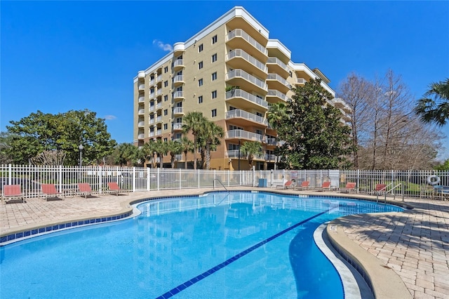 community pool with a patio area and fence