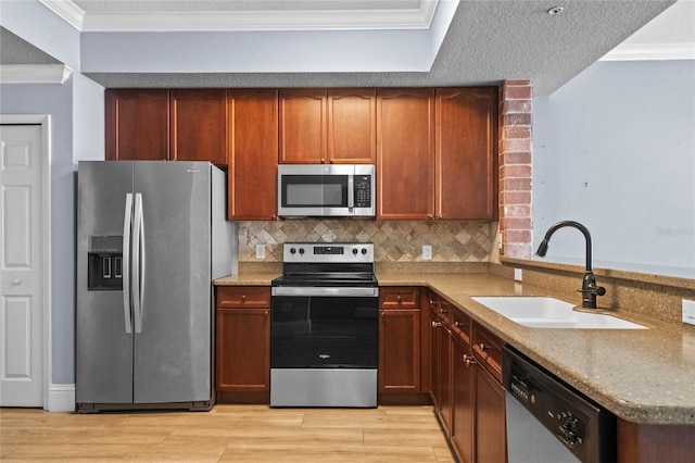 kitchen with crown molding, stainless steel appliances, decorative backsplash, a sink, and light wood-type flooring