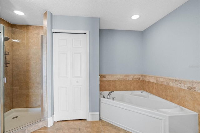 bathroom featuring tile patterned flooring, a textured ceiling, a bath, and a shower stall