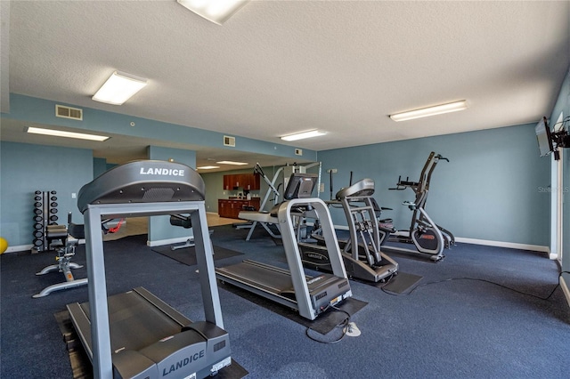 exercise room featuring a textured ceiling, visible vents, and baseboards