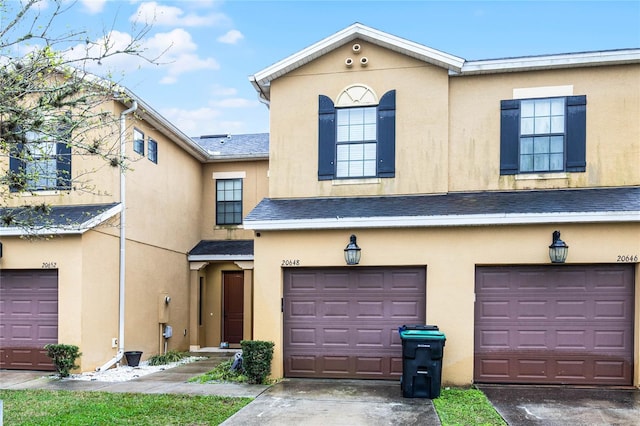 view of property featuring a shingled roof, driveway, an attached garage, and stucco siding