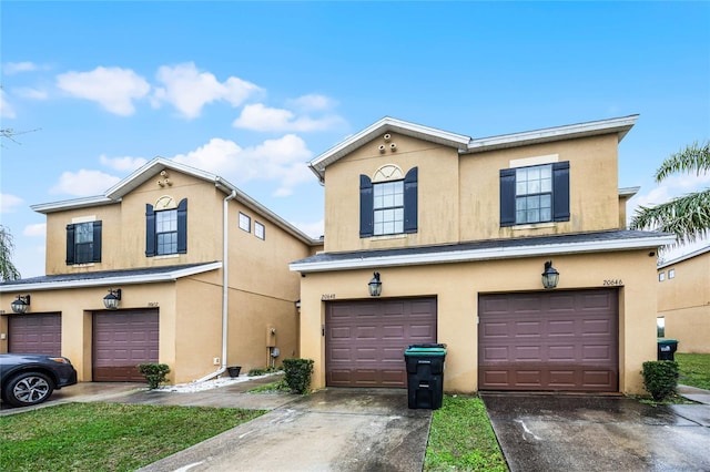 view of front of home featuring driveway, an attached garage, and stucco siding