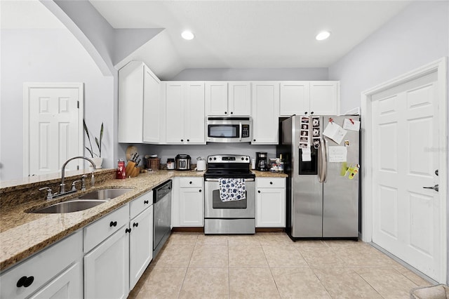 kitchen with appliances with stainless steel finishes, a sink, light stone counters, and light tile patterned floors