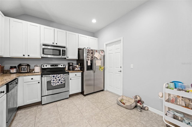 kitchen featuring light tile patterned floors, light stone counters, stainless steel appliances, white cabinetry, and baseboards