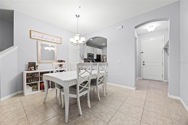 dining area with a chandelier, arched walkways, and light tile patterned flooring