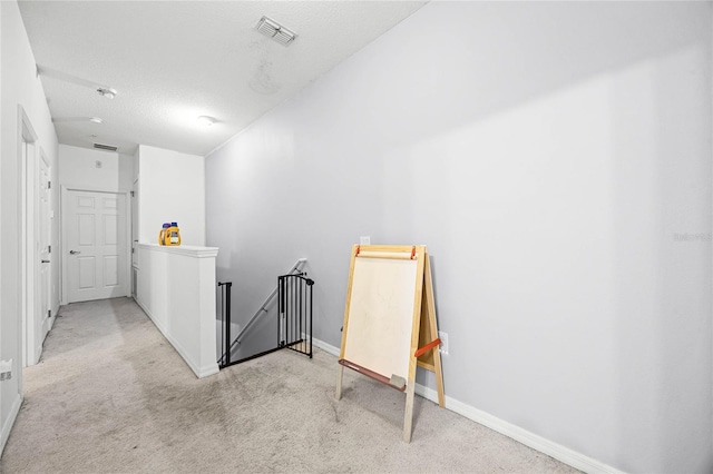 interior space with visible vents, carpet flooring, a textured ceiling, an upstairs landing, and baseboards