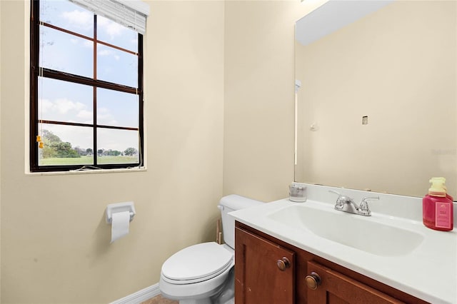 half bathroom featuring vanity, toilet, and baseboards