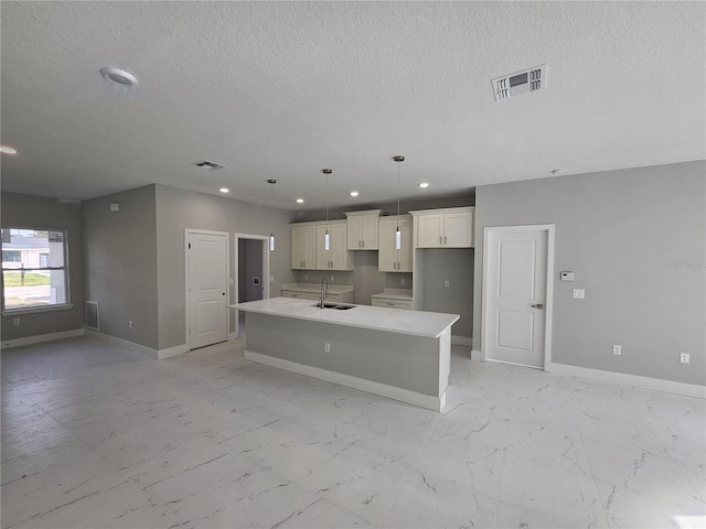 kitchen with marble finish floor, a kitchen island with sink, baseboards, and a sink