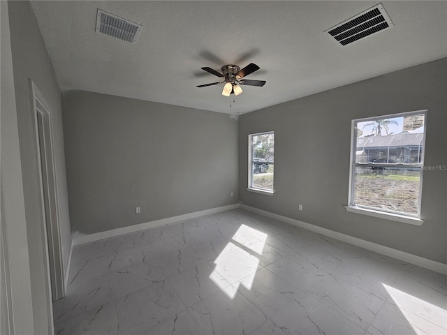 unfurnished room with marble finish floor, a ceiling fan, visible vents, and baseboards