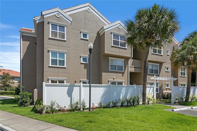 exterior space with fence, a front lawn, and stucco siding