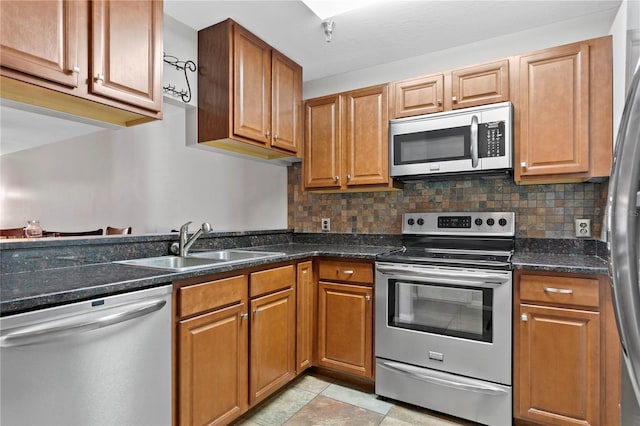 kitchen featuring a sink, appliances with stainless steel finishes, backsplash, and brown cabinets