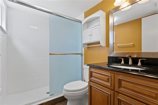 bathroom with toilet, a shower stall, and vanity