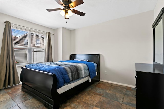 bedroom featuring stone finish flooring, baseboards, and a ceiling fan