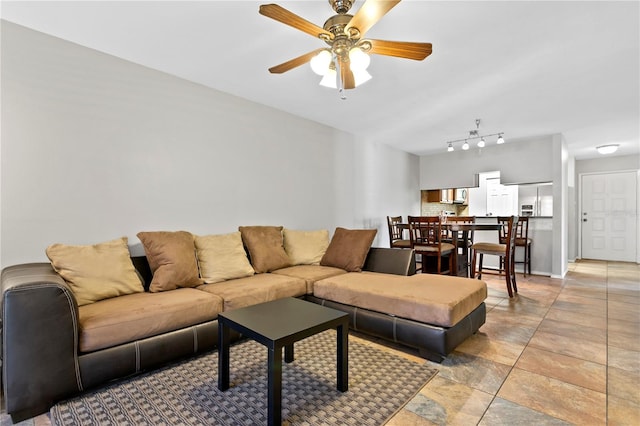 living room with a ceiling fan and baseboards